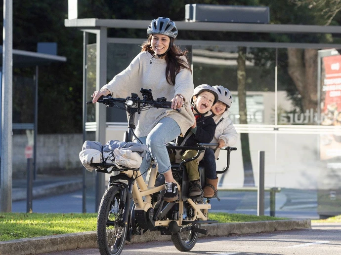Une maman sur un vélo avec des courses à l'avant et un enfant derrière, tern GSD